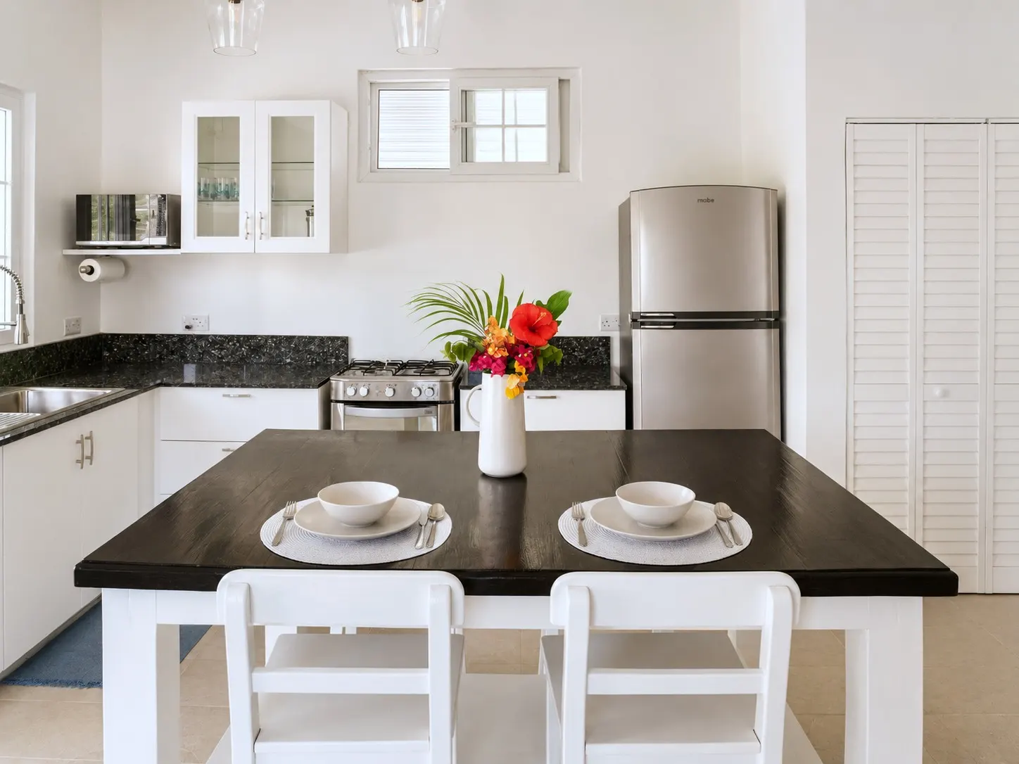 Dining table set for two beneath pendant lighting